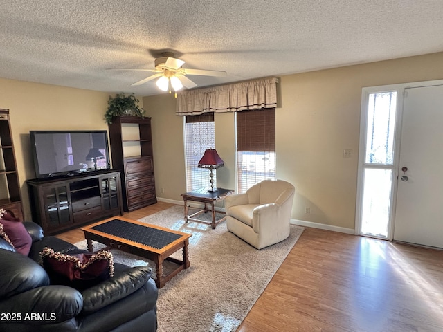 living room featuring a textured ceiling, wood finished floors, a ceiling fan, and baseboards