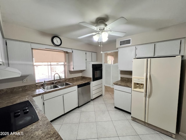 kitchen with light tile patterned floors, a sink, visible vents, black appliances, and dark countertops