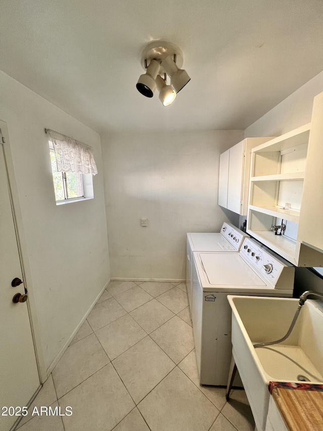 clothes washing area with cabinet space, light tile patterned floors, baseboards, separate washer and dryer, and a sink