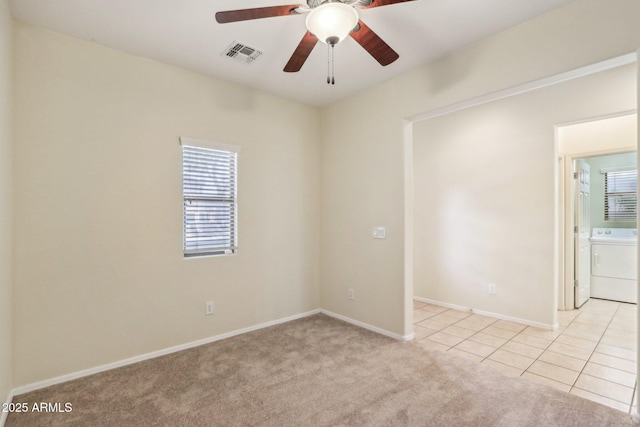 empty room featuring washer / clothes dryer, a wealth of natural light, light colored carpet, and ceiling fan