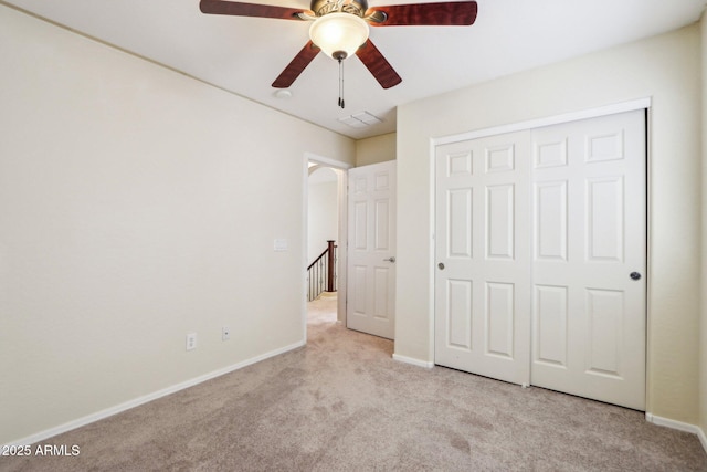 unfurnished bedroom featuring light colored carpet, ceiling fan, and a closet