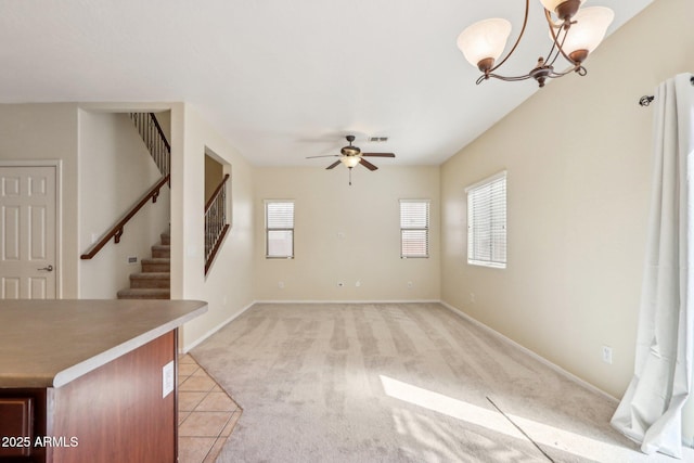 unfurnished living room with light colored carpet and ceiling fan with notable chandelier