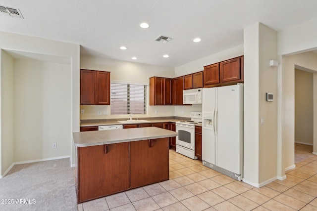 kitchen featuring light tile patterned floors, white appliances, sink, a kitchen island, and a kitchen bar