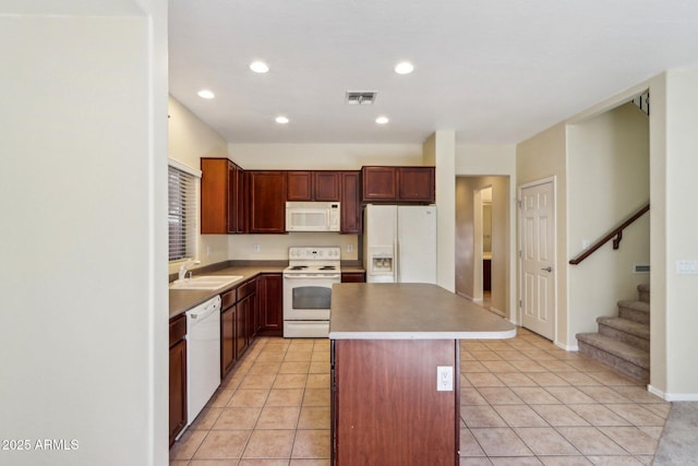 kitchen featuring light tile patterned flooring, a center island, sink, and white appliances