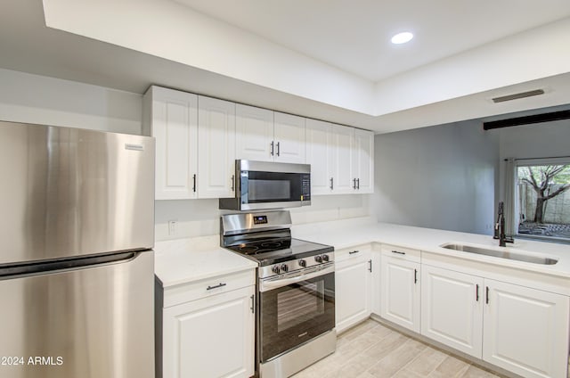 kitchen featuring light wood-type flooring, white cabinetry, sink, and appliances with stainless steel finishes