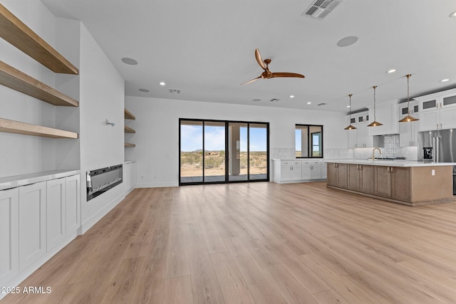 34198 S State Route 89th Hwy, Wickenburg, AZ 85390 - unfurnished living room featuring a sink, recessed lighting, a glass covered fireplace, light wood-style floors, and ceiling fan