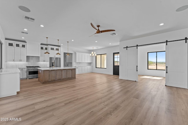 34198 S State Route 89th Hwy, Wickenburg, AZ 85390 - kitchen with a barn door, appliances with stainless steel finishes, open floor plan, tasteful backsplash, and a ceiling fan