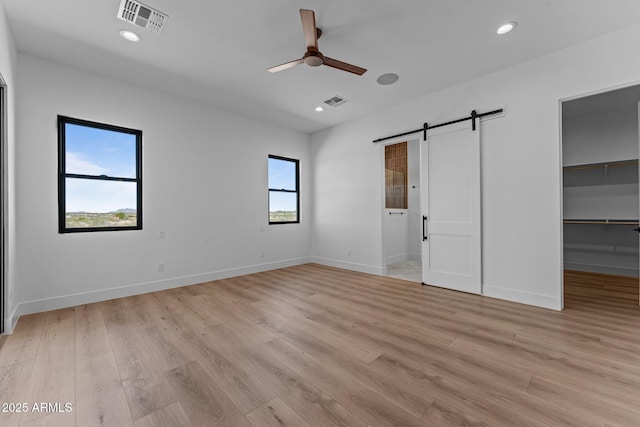 34198 S State Route 89th Hwy, Wickenburg, AZ 85390 - unfurnished bedroom with a barn door, light wood-type flooring, a spacious closet, recessed lighting, and baseboards