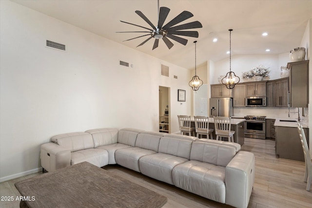 13361 N 99th Pl, Scottsdale, AZ 85260 - living room with a ceiling fan, light wood-style floors, high vaulted ceiling, recessed lighting, and a chandelier