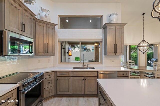 13361 N 99th Pl, Scottsdale, AZ 85260 - kitchen featuring stainless steel appliances, a chandelier, light countertops, backsplash, and decorative light fixtures