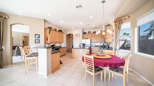 kitchen with kitchen peninsula, stainless steel refrigerator with ice dispenser, pendant lighting, a kitchen island, and light tile patterned flooring