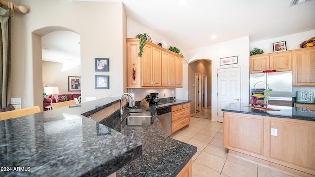 kitchen with dark stone counters, sink, light tile patterned floors, light brown cabinetry, and stainless steel appliances