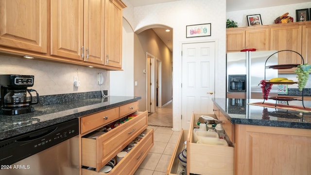 kitchen featuring light tile patterned floors, light brown cabinetry, appliances with stainless steel finishes, and dark stone counters