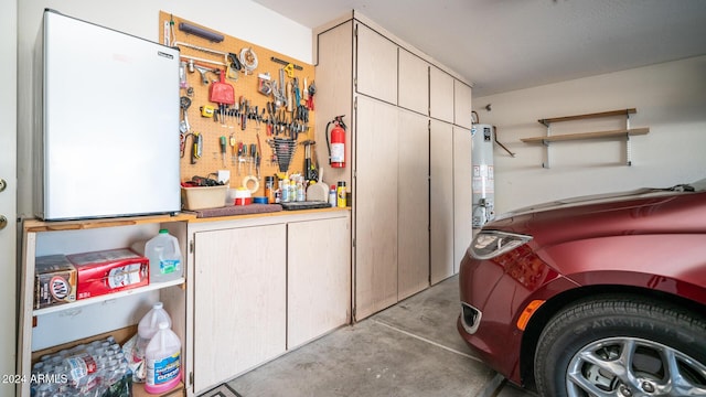 garage featuring a workshop area, refrigerator, and gas water heater