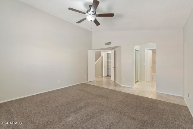 unfurnished bedroom featuring light carpet, vaulted ceiling, ensuite bathroom, and ceiling fan