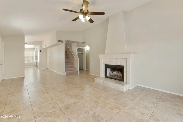 unfurnished living room featuring ceiling fan, a tiled fireplace, light tile patterned floors, and vaulted ceiling