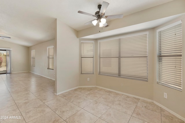 tiled spare room featuring ceiling fan and vaulted ceiling