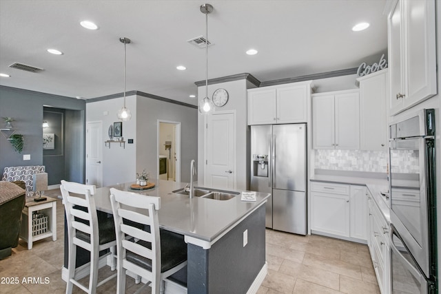 kitchen featuring visible vents, a sink, ornamental molding, and stainless steel appliances