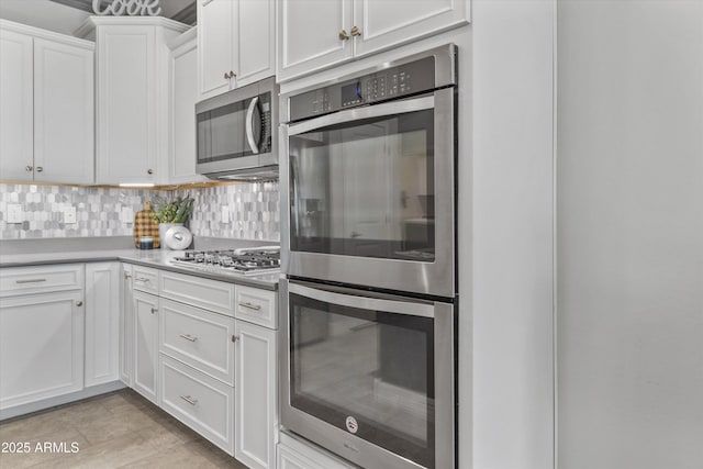 kitchen featuring light countertops, decorative backsplash, white cabinetry, and stainless steel appliances