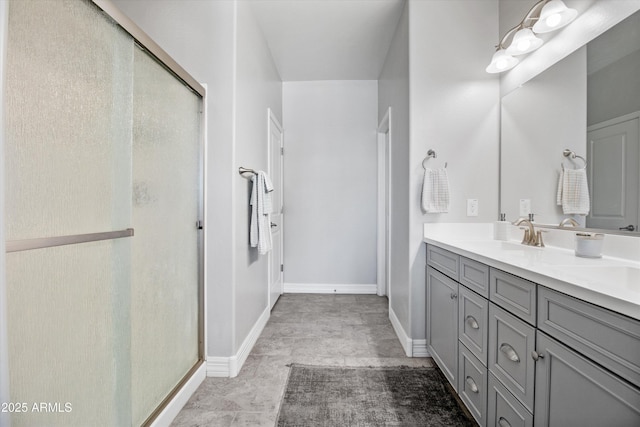 full bathroom with a sink, baseboards, a shower stall, and double vanity