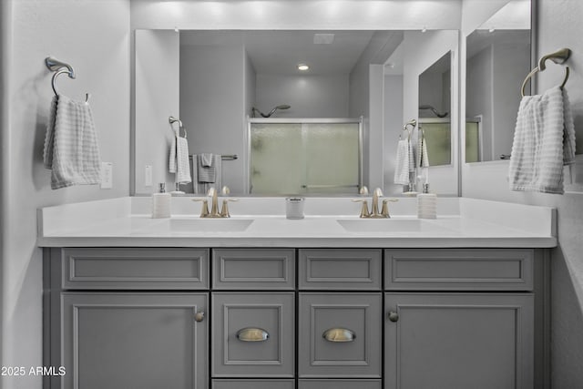 bathroom with a sink, a stall shower, and double vanity