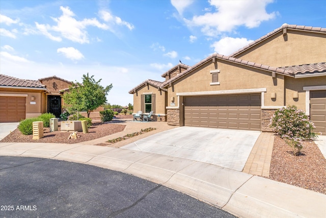 view of front of house with an attached garage, driveway, a tile roof, and stucco siding