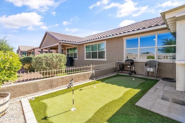 rear view of property with fence, a tile roof, a patio area, and stucco siding