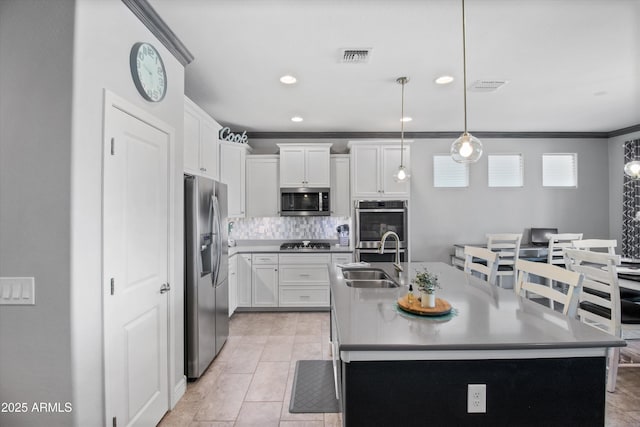 kitchen with appliances with stainless steel finishes, a sink, an island with sink, backsplash, and ornamental molding