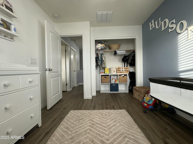 bedroom with dark wood-type flooring, baseboards, visible vents, and a closet