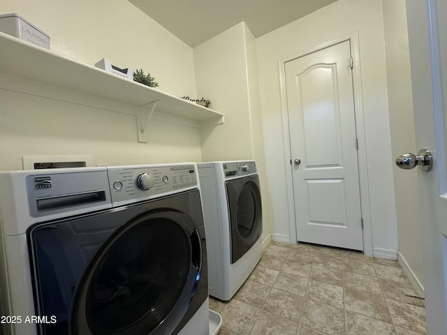 laundry area with baseboards, separate washer and dryer, light tile patterned flooring, and laundry area
