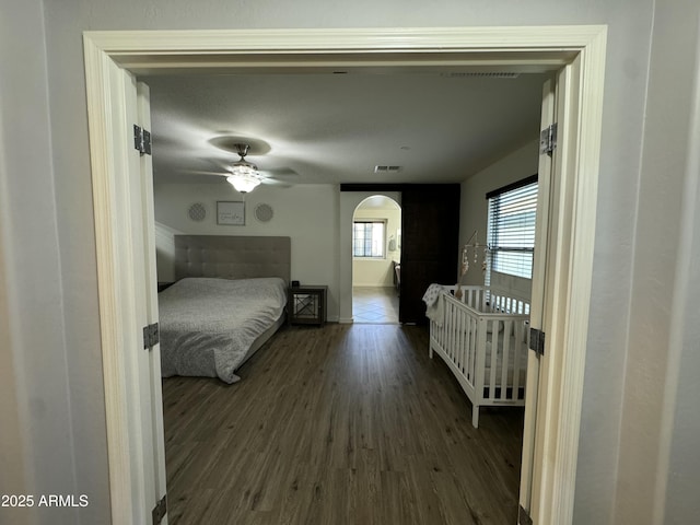 bedroom with arched walkways, visible vents, and wood finished floors