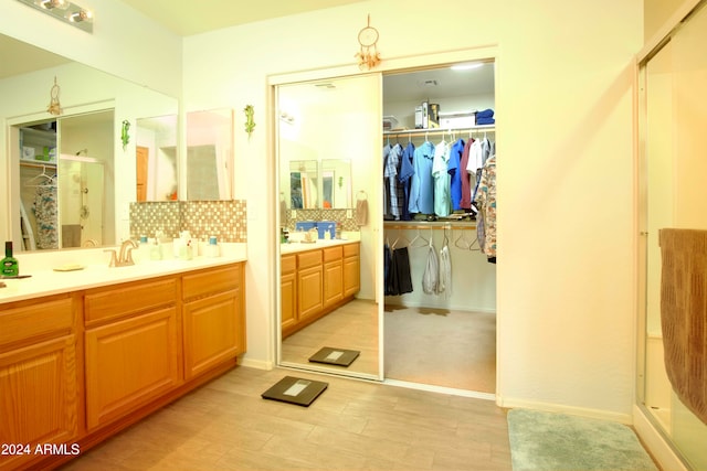 bathroom featuring vanity, decorative backsplash, a shower with door, and wood-type flooring