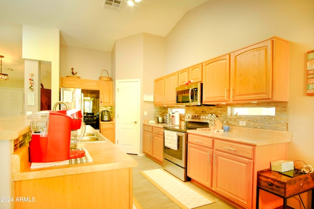 kitchen with light brown cabinets, light wood-type flooring, appliances with stainless steel finishes, and tasteful backsplash