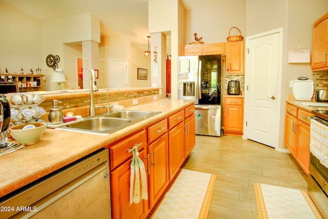 kitchen with tasteful backsplash, appliances with stainless steel finishes, sink, and light hardwood / wood-style floors