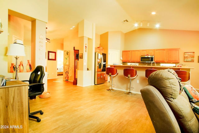 interior space with light hardwood / wood-style floors, track lighting, and high vaulted ceiling