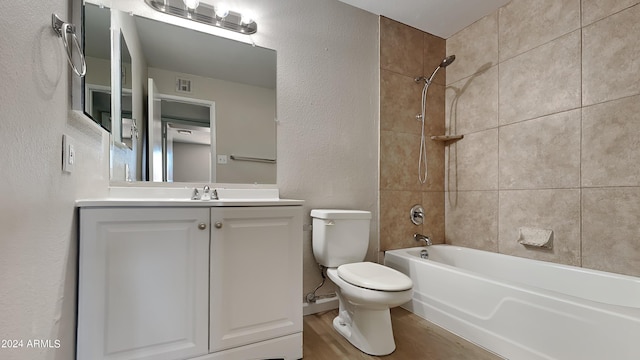 full bathroom with vanity, wood-type flooring, tiled shower / bath combo, and toilet