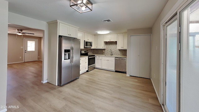 kitchen featuring ceiling fan, stainless steel appliances, light hardwood / wood-style floors, decorative backsplash, and white cabinets