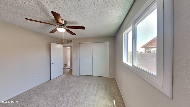 unfurnished bedroom featuring a textured ceiling, light colored carpet, and ceiling fan