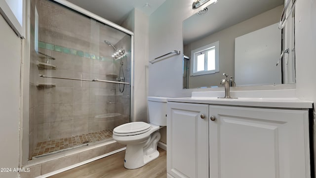 bathroom with toilet, vanity, a shower with door, and hardwood / wood-style flooring