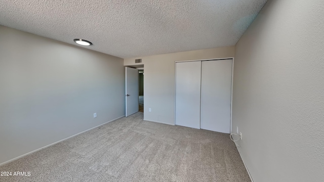 unfurnished bedroom featuring a closet, light colored carpet, and a textured ceiling