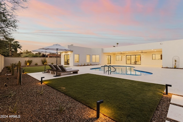 pool at dusk with a patio area and a yard