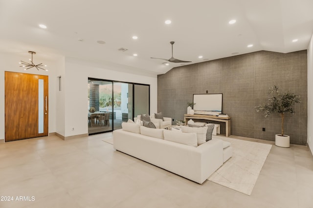 living room with lofted ceiling and ceiling fan with notable chandelier