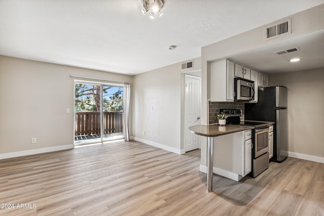 kitchen with backsplash, stainless steel appliances, kitchen peninsula, and light hardwood / wood-style floors