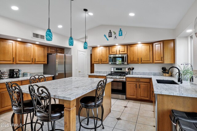 4493 E Desert Sands Dr, Chandler, AZ 85249 - kitchen featuring appliances with stainless steel finishes, a sink, brown cabinets, a center island, and vaulted ceiling