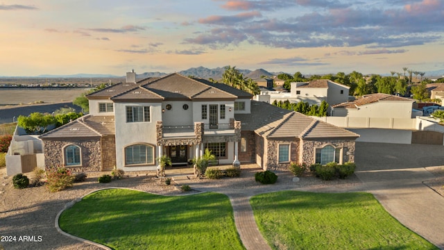 mediterranean / spanish-style home featuring a balcony and a lawn