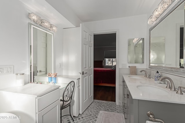 ensuite bathroom featuring double vanity, connected bathroom, and a sink