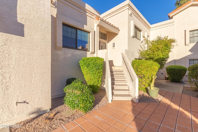 view of exterior entry featuring a patio area and stucco siding