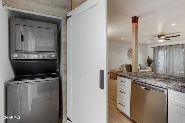 kitchen with white cabinetry, dishwasher, stacked washing maching and dryer, and dark stone counters