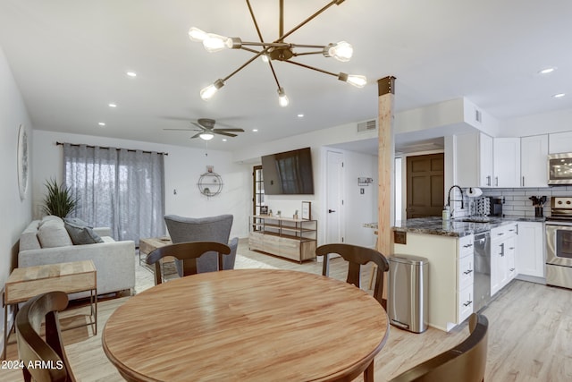 dining space with light hardwood / wood-style floors, sink, and ceiling fan with notable chandelier