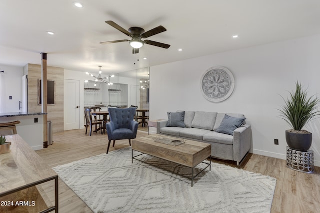 living room featuring light wood-type flooring and ceiling fan with notable chandelier